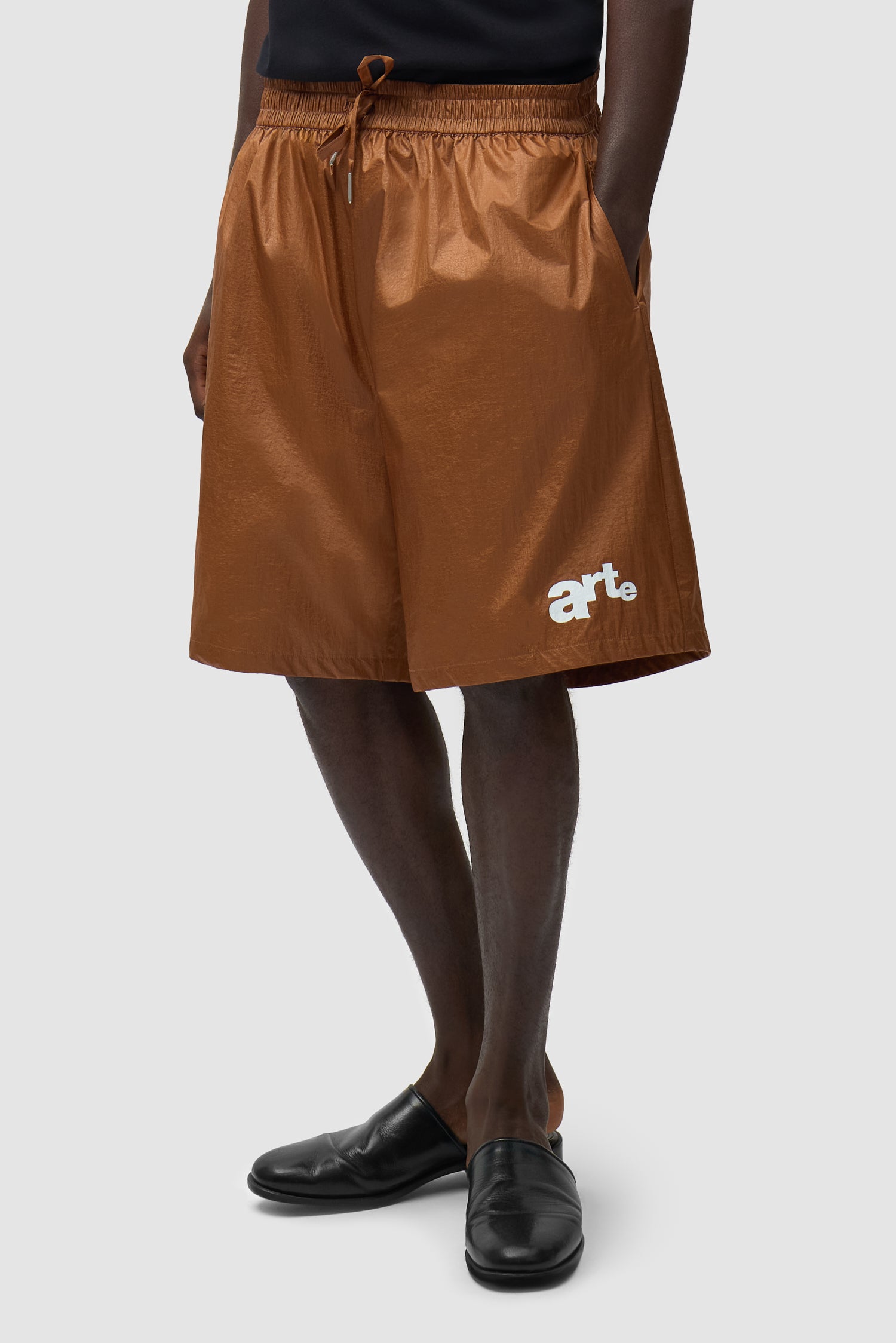 Short à grand logo orange porté par un mannequin, vue de profil à mi-corps