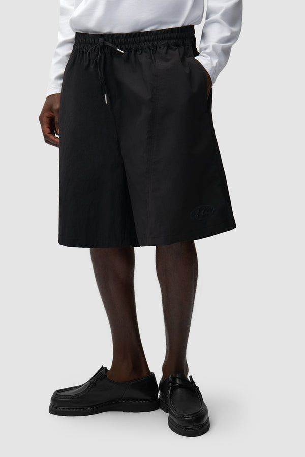 Distorted Shorts in Black worn by a model, half-body side view