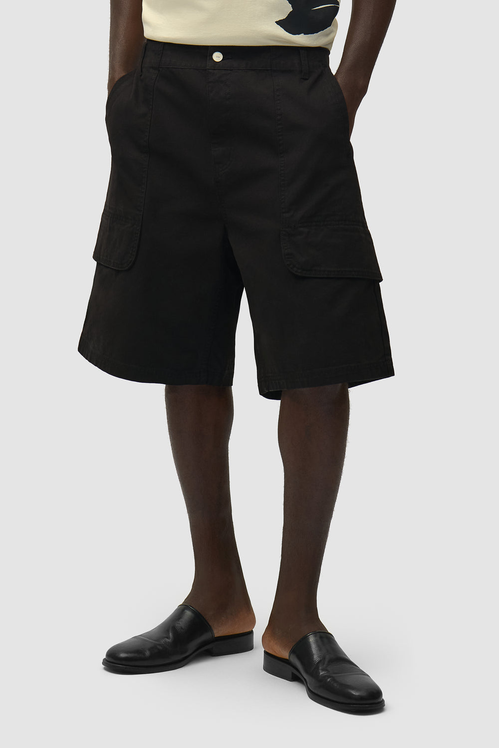 Short cargo en toile noir porté par un mannequin, vue de face en demi-corps