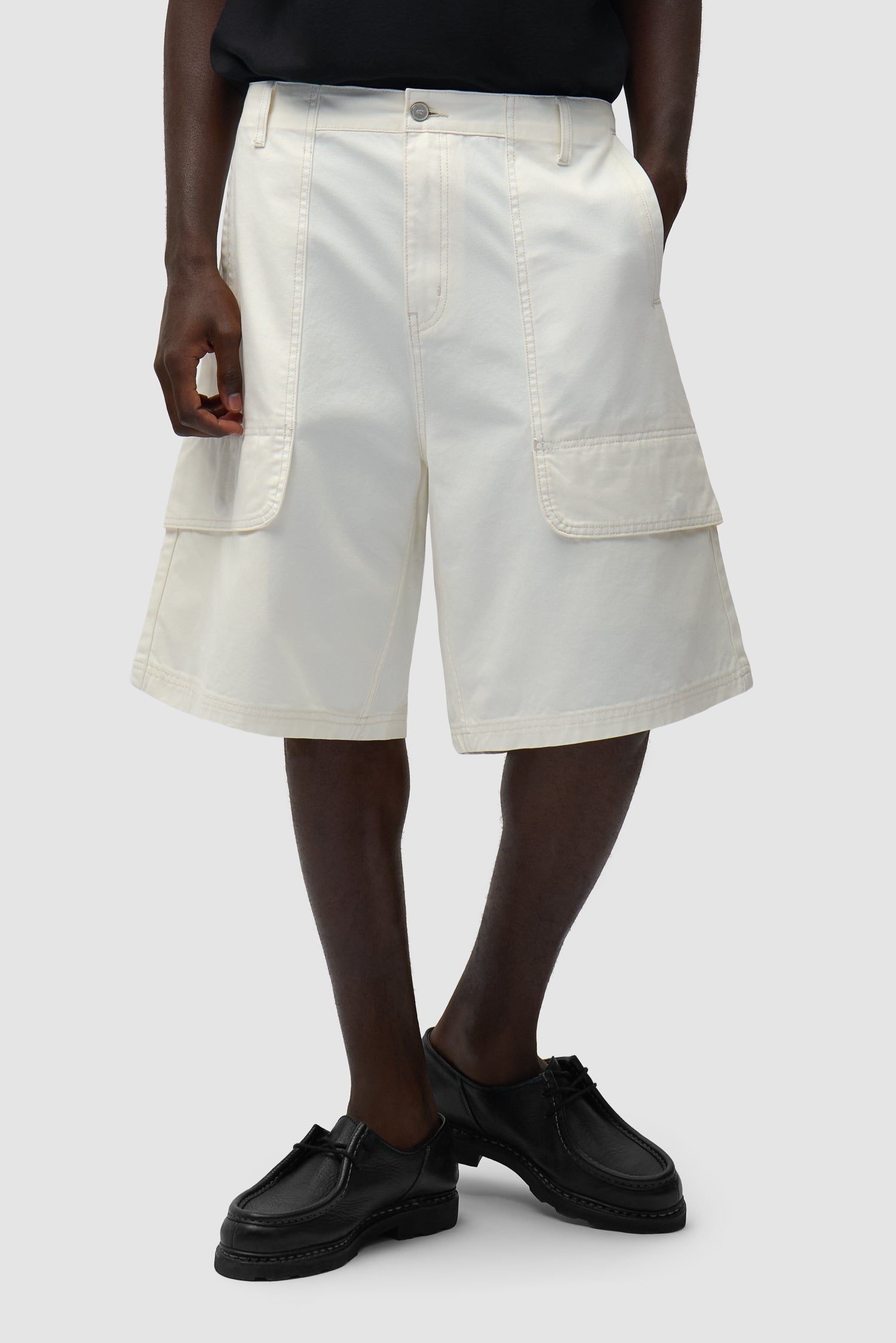 Short cargo en toile couleur crème porté par un mannequin, vue de face en demi-corps