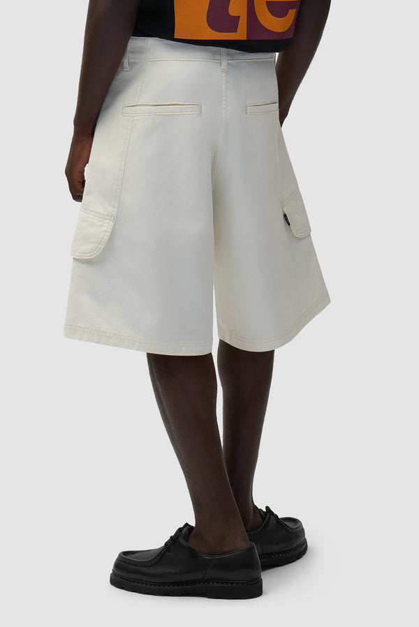 Canvas Cargo Shorts in Cream worn by a model, half-body side view