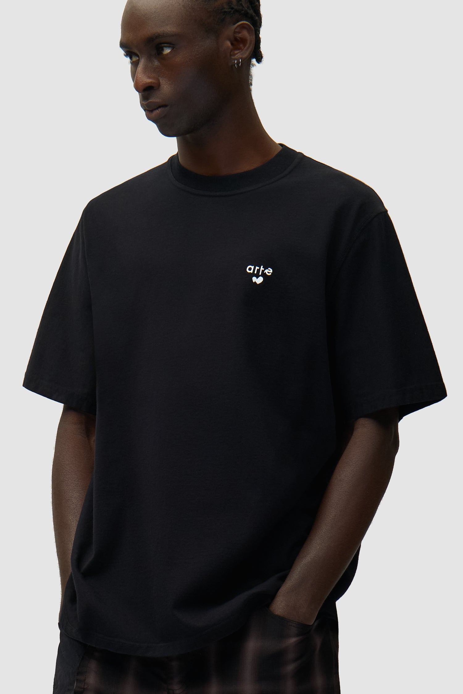 T-shirt noir avec logo en forme de cœur porté par un mannequin, vue détaillée du haut du corps