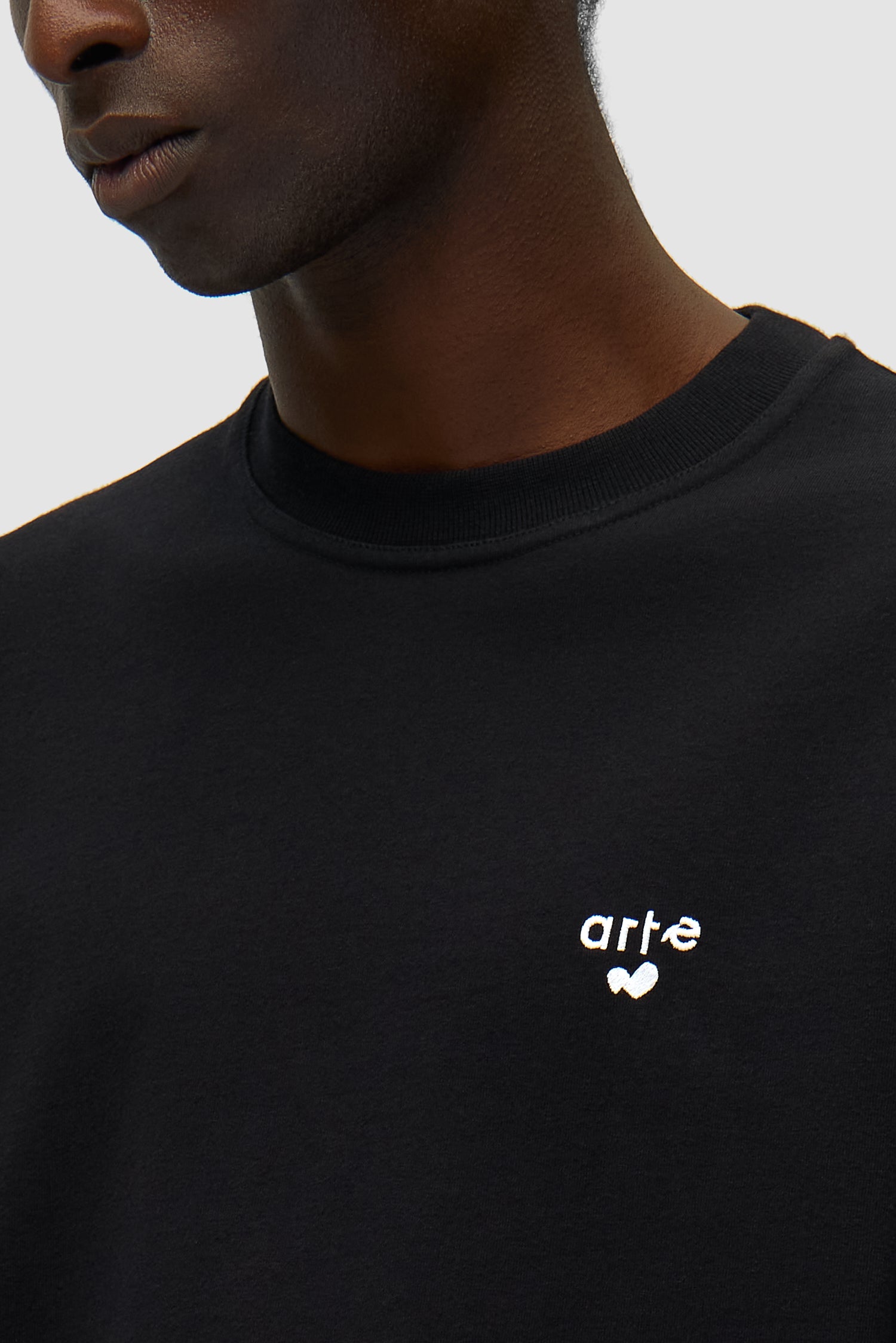 Vue détaillée du t-shirt noir avec logo en forme de cœur, montrant le logo sur le devant.