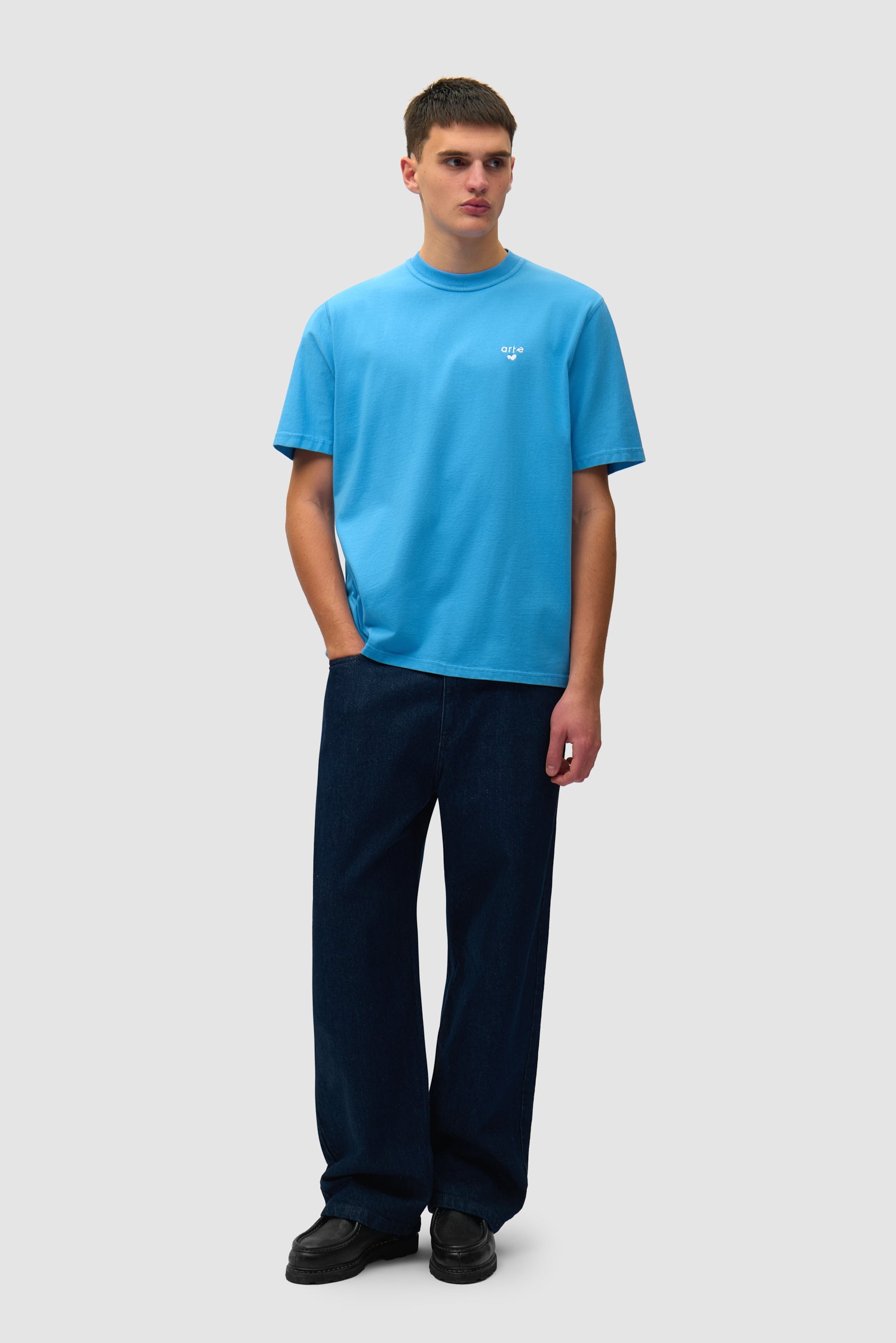 T-shirt bleu avec logo en forme de cœur porté par un mannequin, vue de face en pied