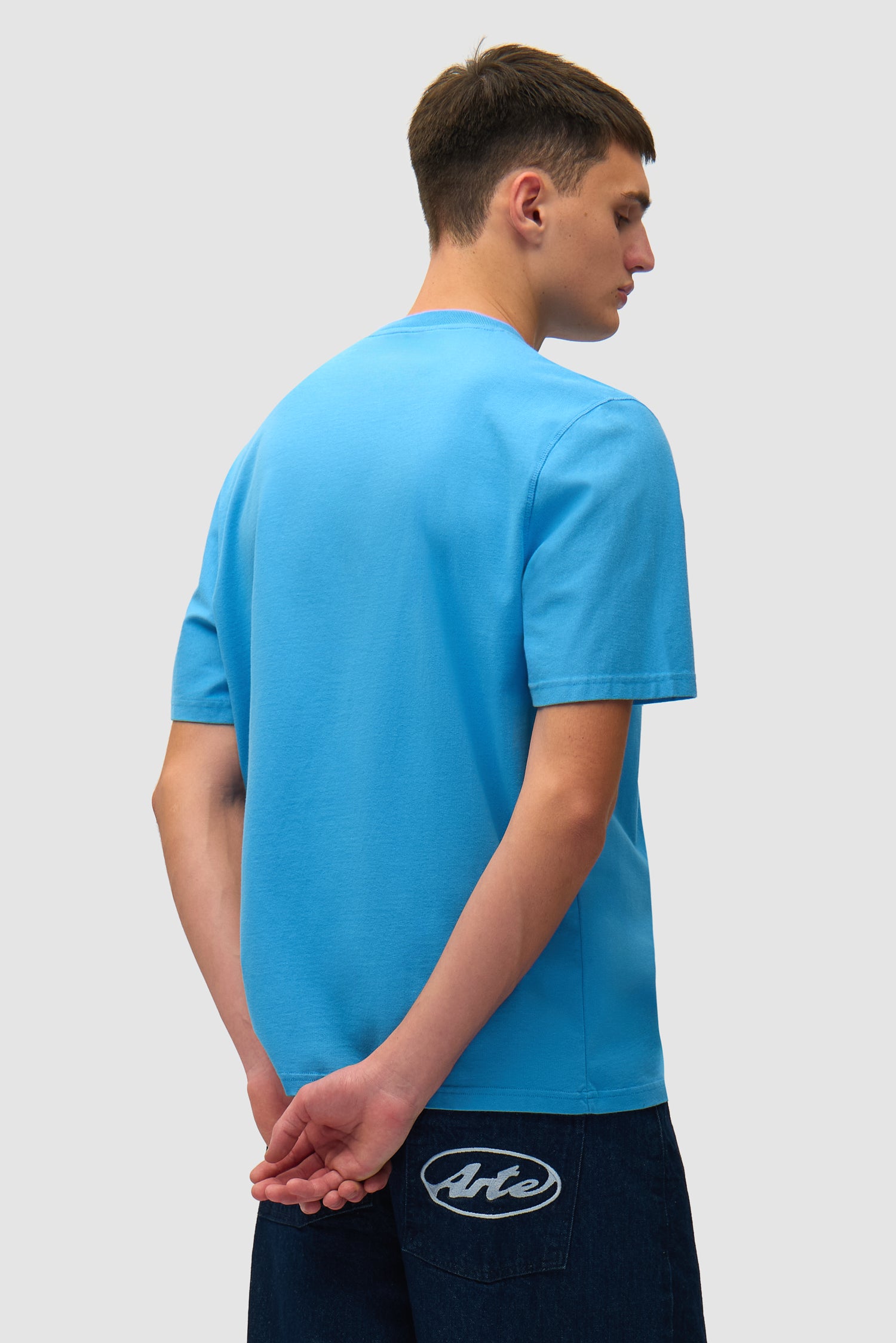 T-shirt bleu avec logo en forme de cœur porté par un mannequin, vue de dos à mi-corps