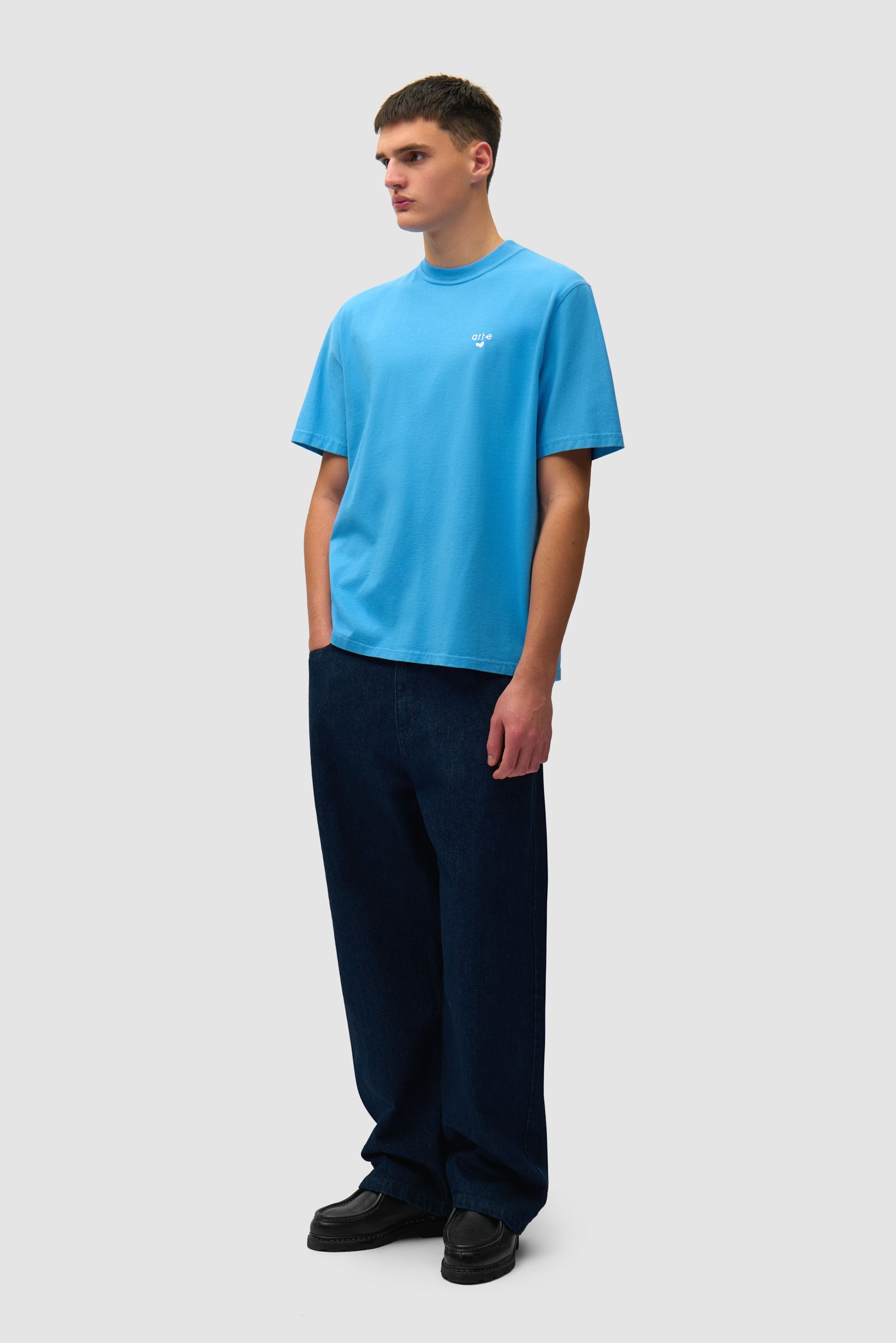 T-shirt bleu avec logo en forme de cœur porté par un mannequin, vue de profil en pied