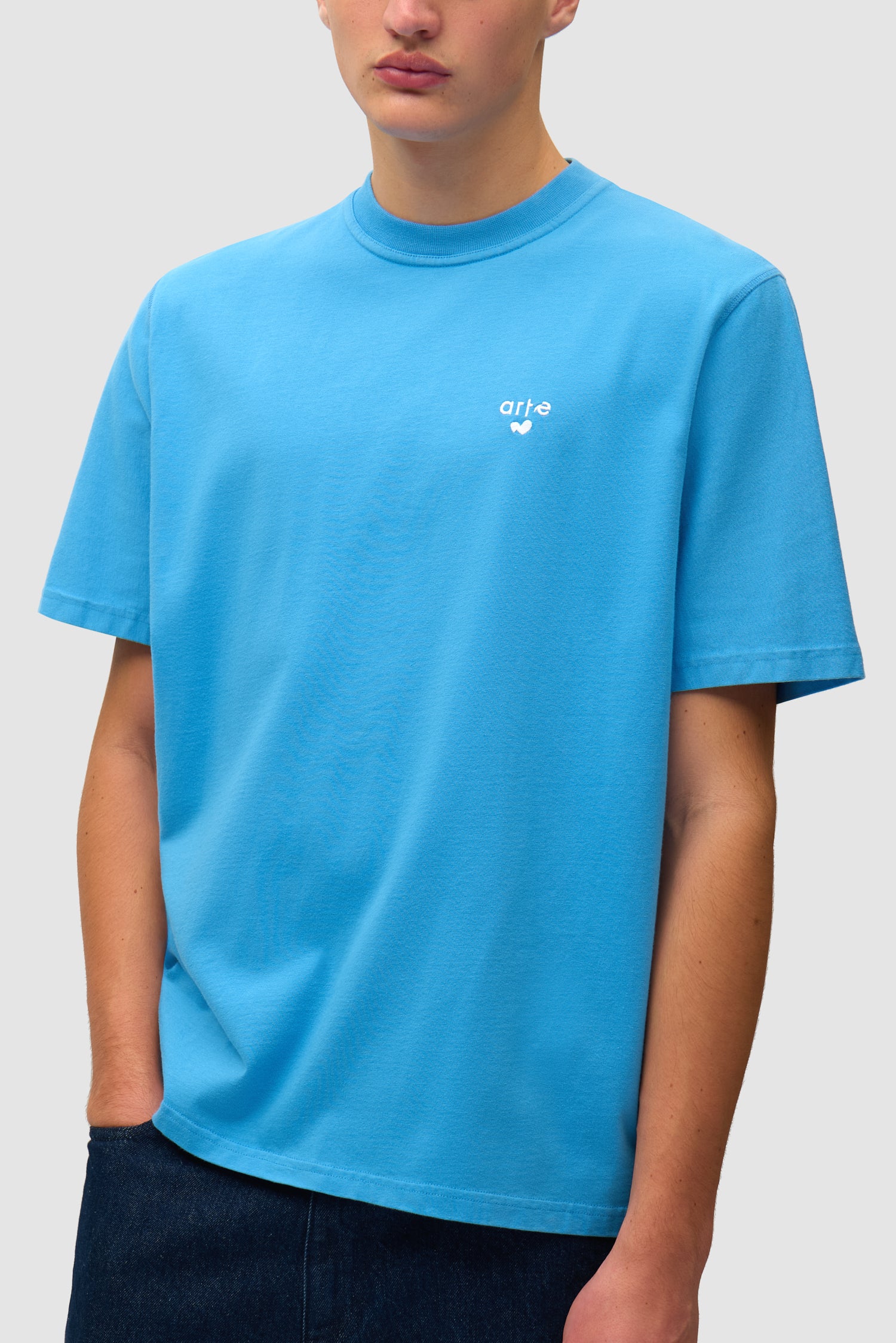 T-shirt bleu avec logo en forme de cœur porté par un mannequin, vue détaillée du haut du corps