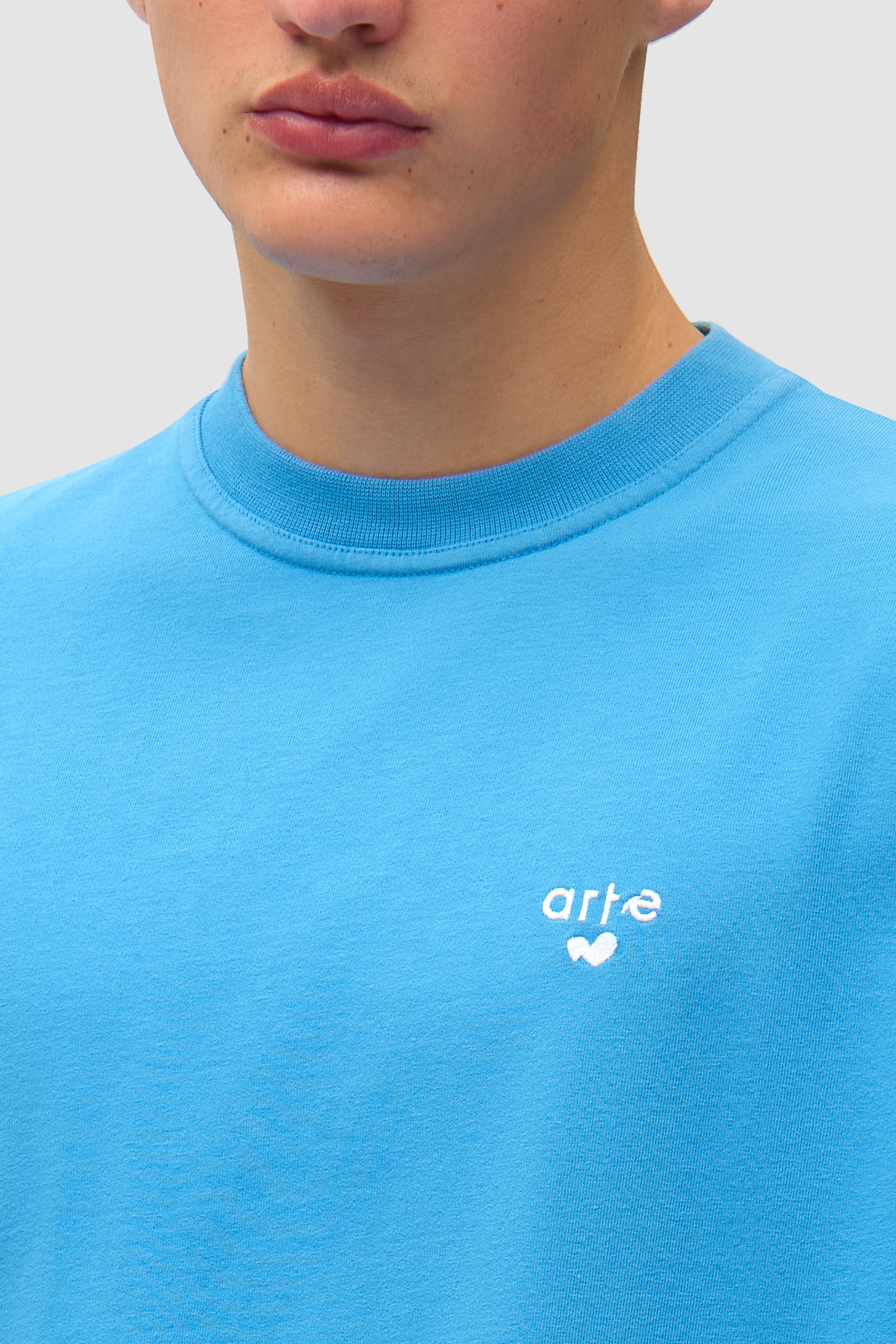 Vue détaillée du t-shirt bleu avec logo en forme de cœur, montrant le logo sur le devant.