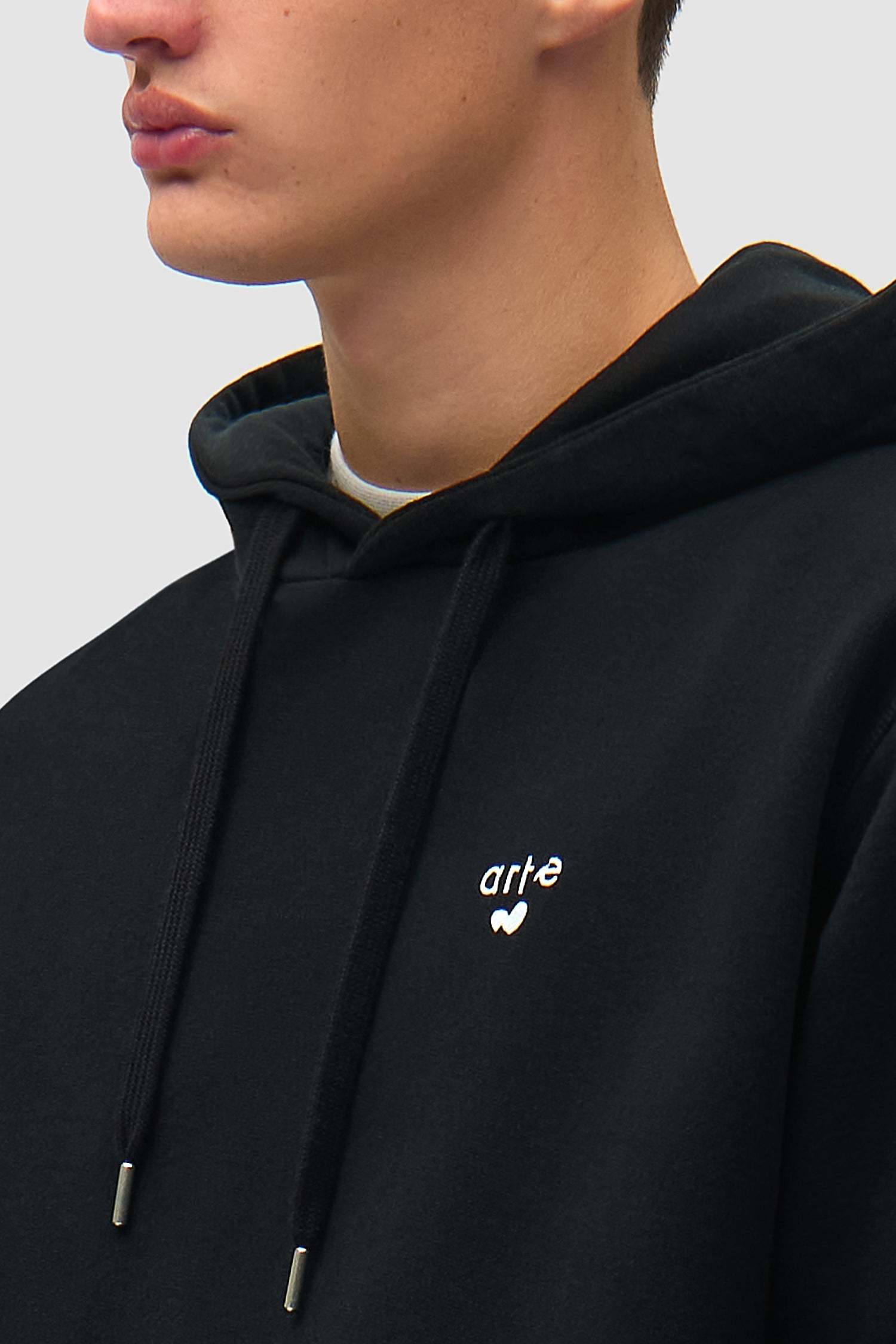 Vue détaillée du sweat à capuche noir avec logo en forme de cœur, montrant le logo