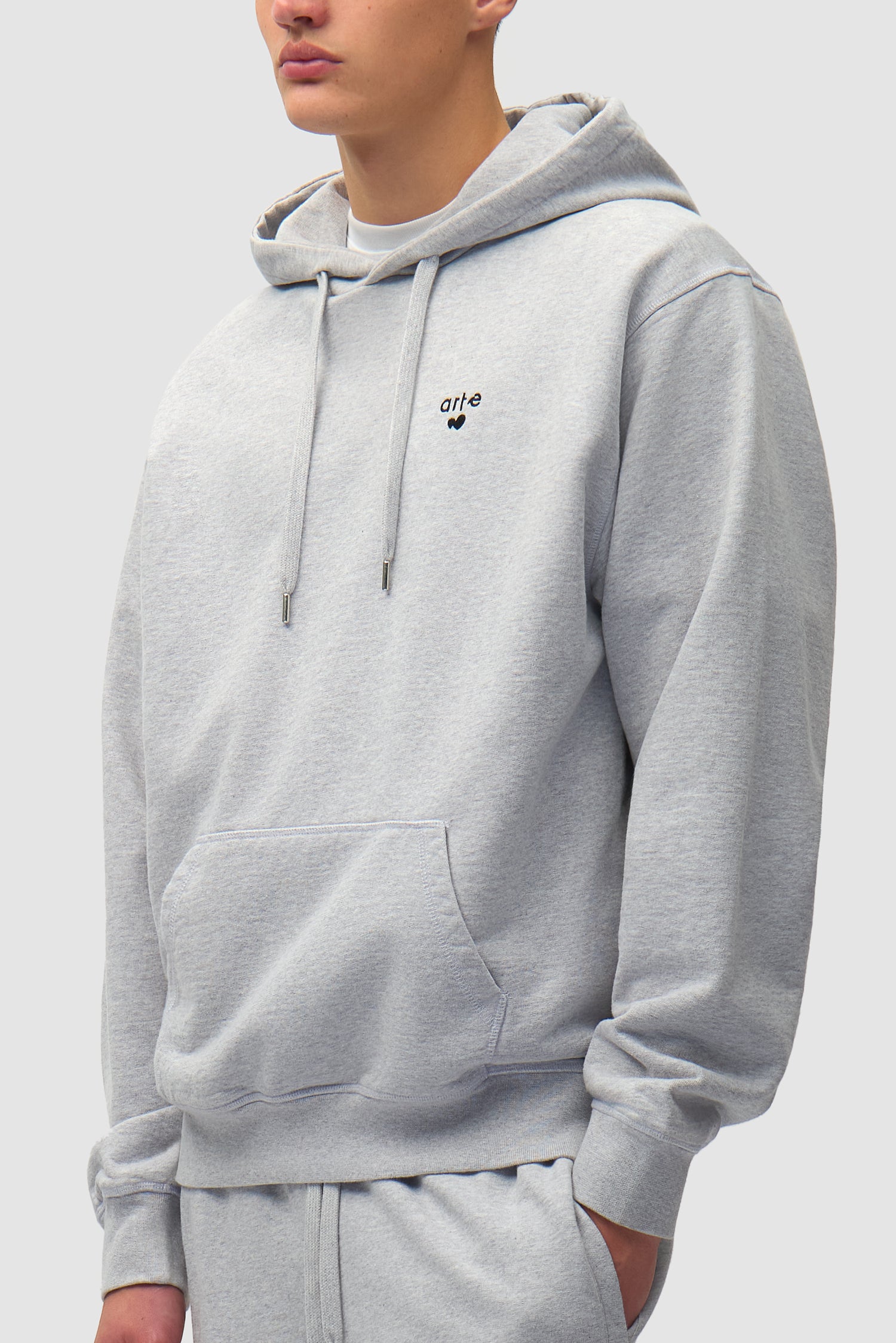 Heart Logo Hoodie in Grey worn by a model, half-body side view