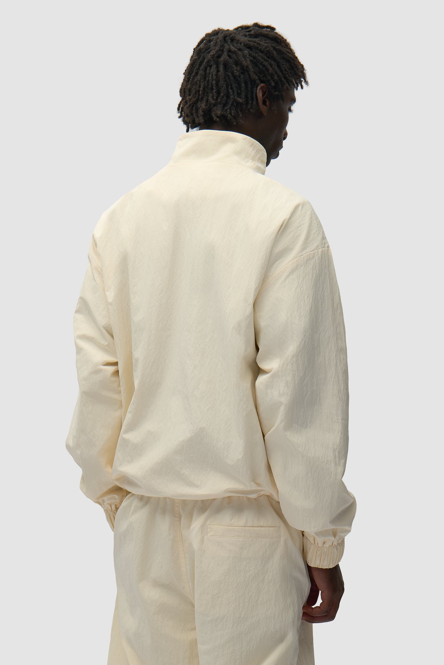Squared Track Jacket in Cream worn by a model, half-body back view