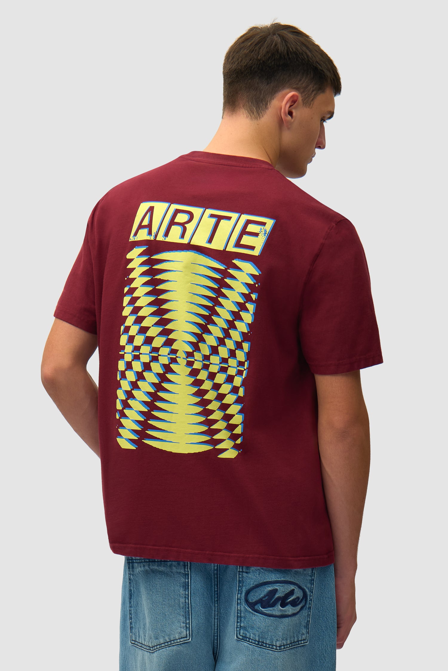 T-shirt à dos imprimé abstrait couleur bordeaux porté par un mannequin, vue de dos à mi-corps
