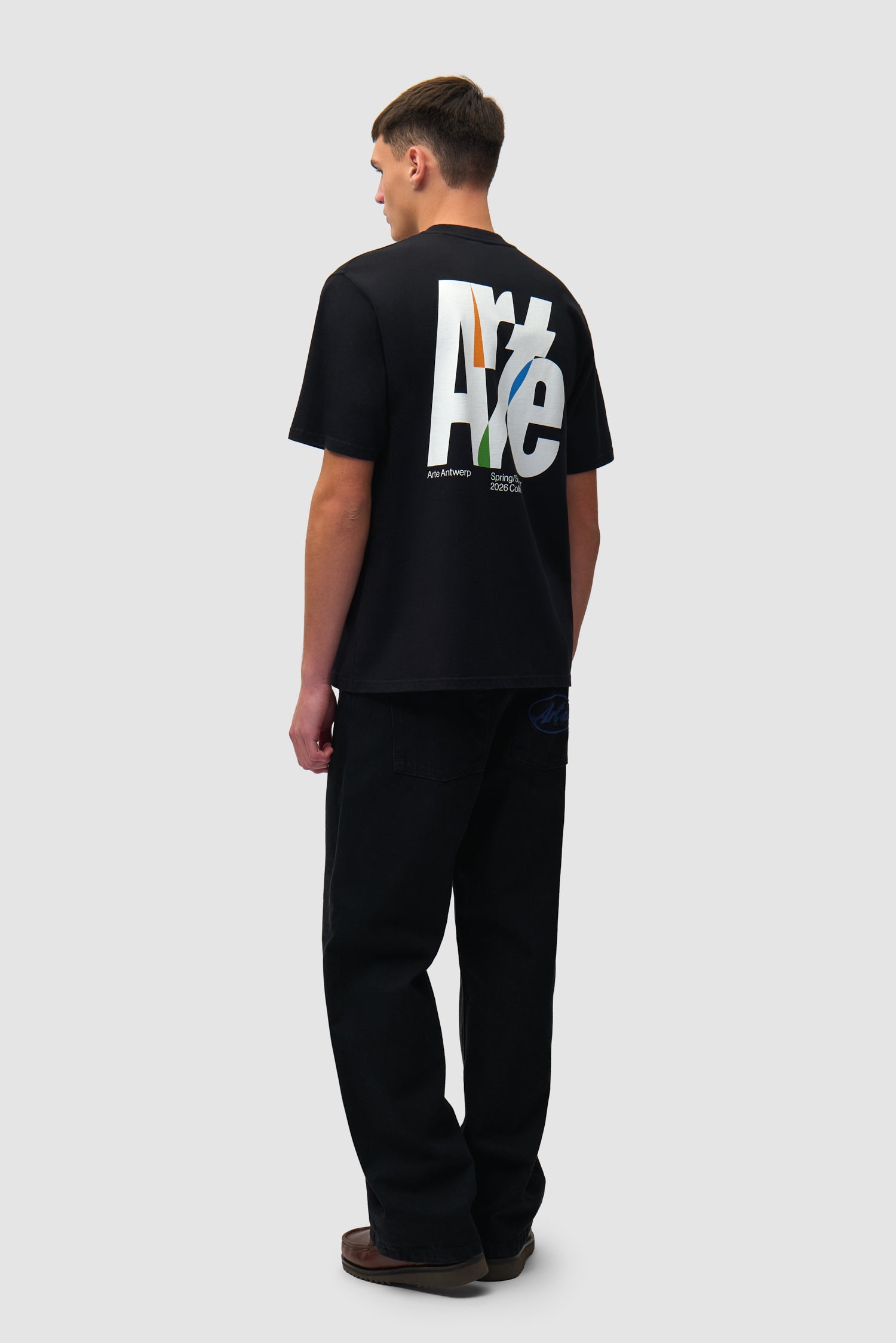 T-shirt noir à grand logo dans le dos porté par un mannequin, vue de profil en pied