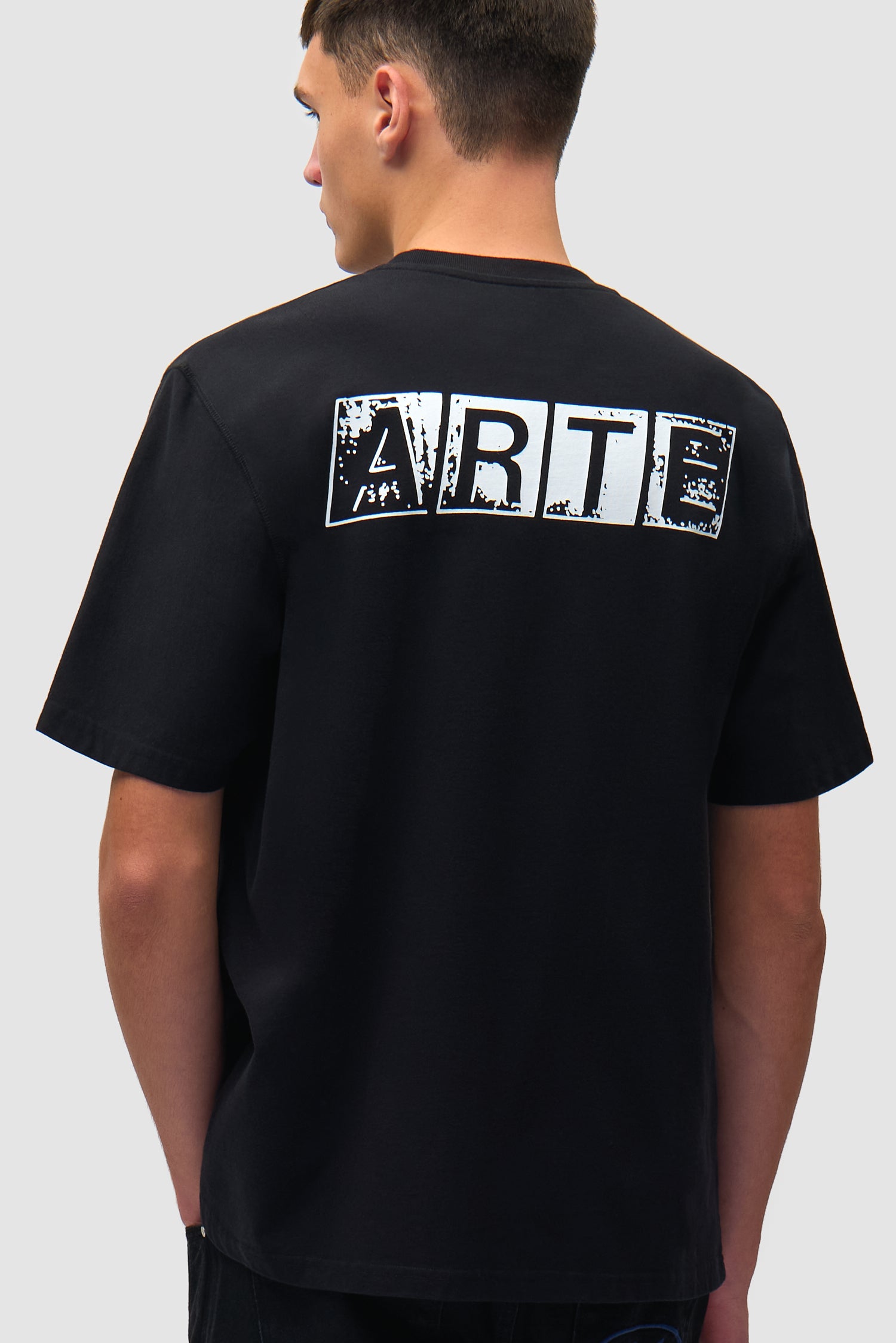 T-shirt noir délavé imprimé dans le dos porté par un mannequin, vue de profil à mi-corps