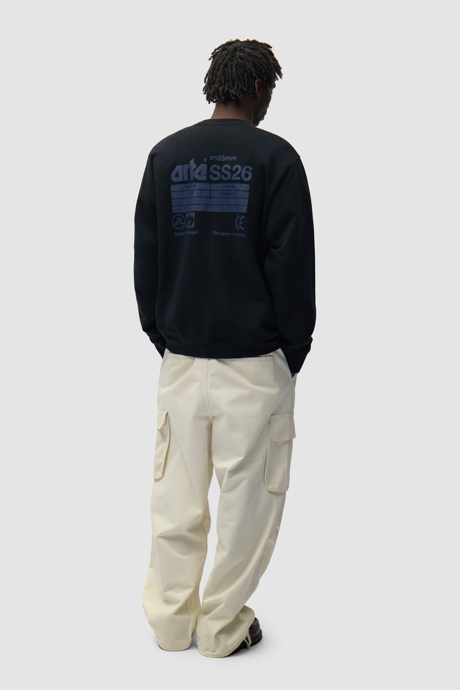 Dos SS26 Crewneck en noir porté par un mannequin, vue de profil en pied