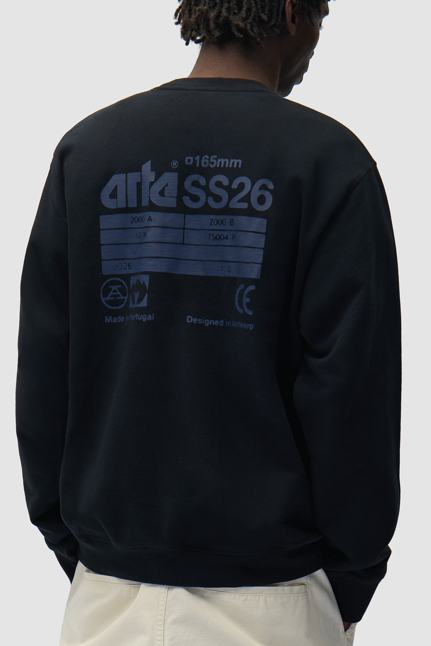 Dos SS26 Crewneck en noir porté par un mannequin, vue de profil à mi-corps