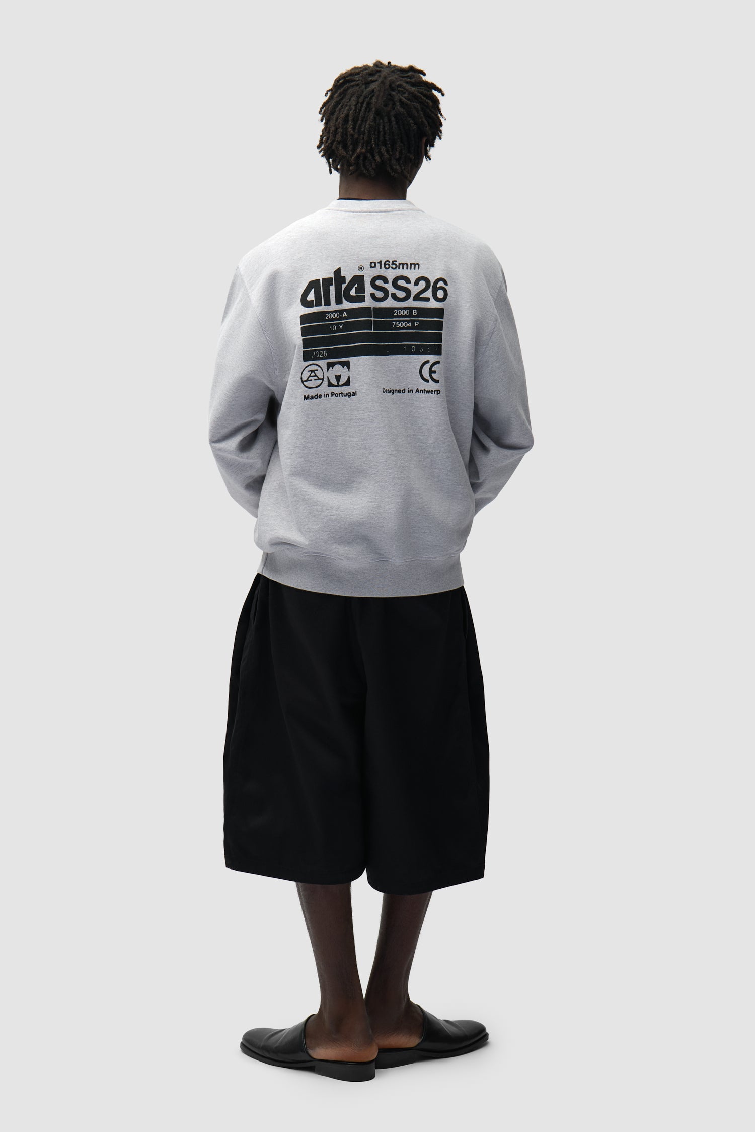 Dos SS26 Crewneck en gris porté par un mannequin, vue de profil en pied