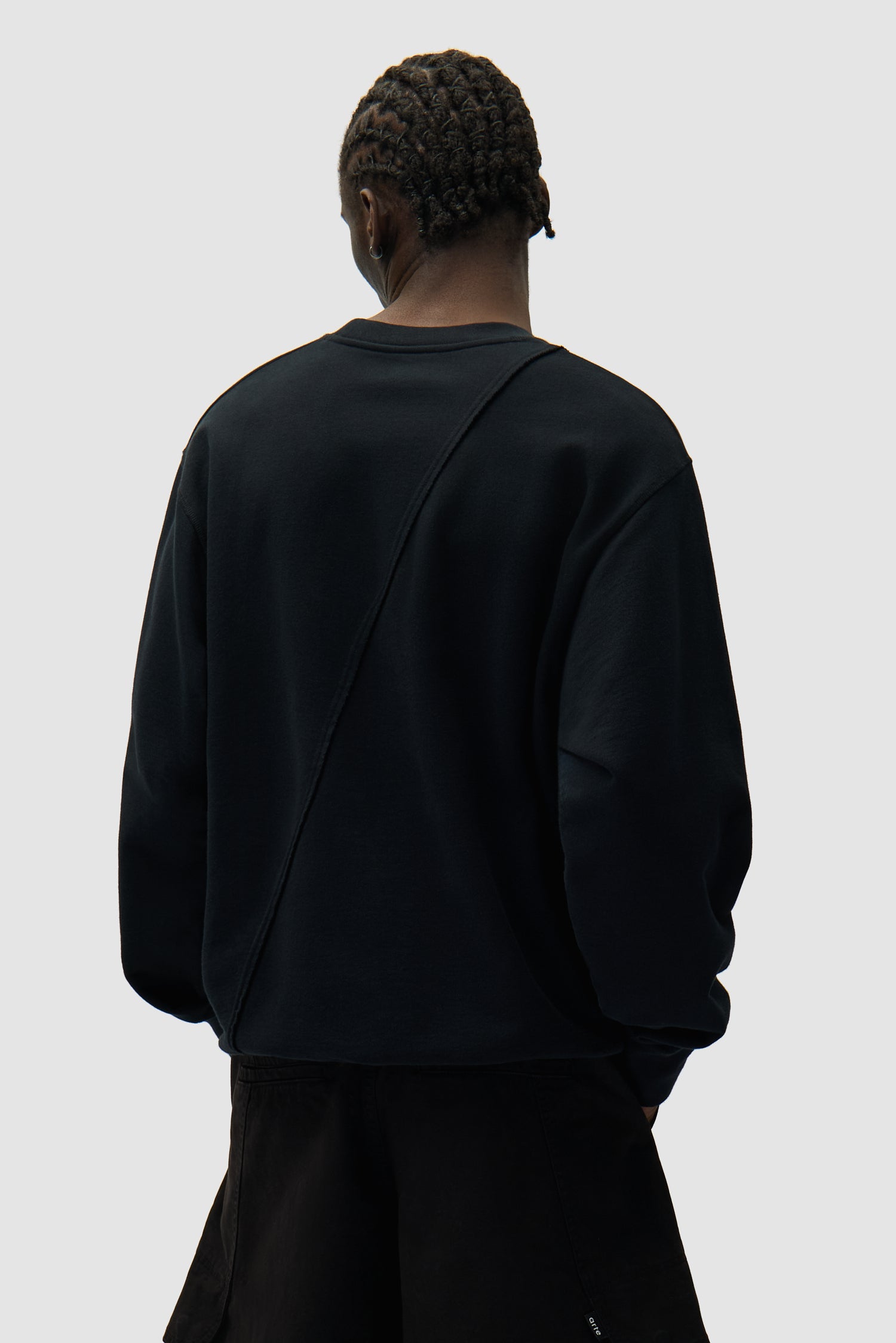Circle Logo Embroidery Sweater in Black worn by a model, half-body back view