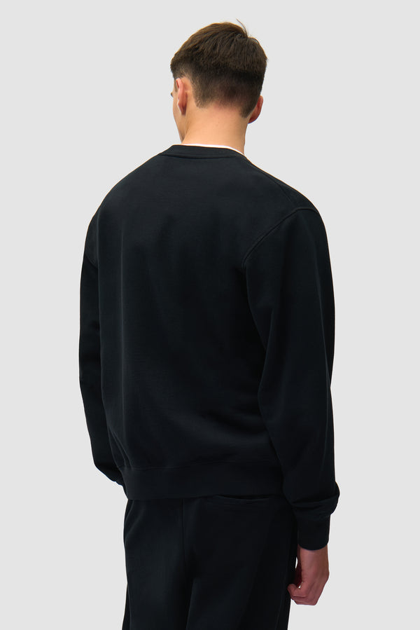 Heart Logo Crewneck in Black worn by a model, half-body back view
