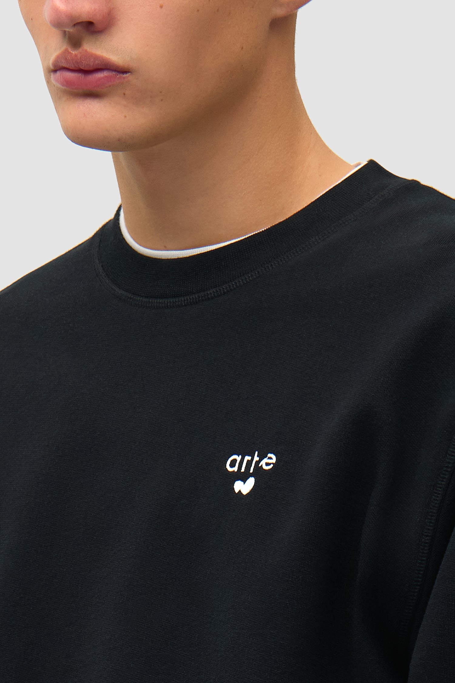 Vue détaillée du t-shirt à col rond noir avec logo en forme de cœur, montrant le logo