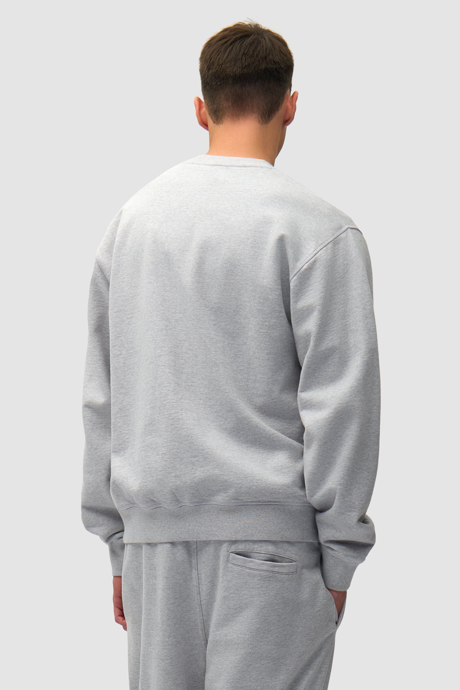 T-shirt à col rond avec logo en forme de cœur, couleur grise, porté par un mannequin, vue de dos à mi-corps