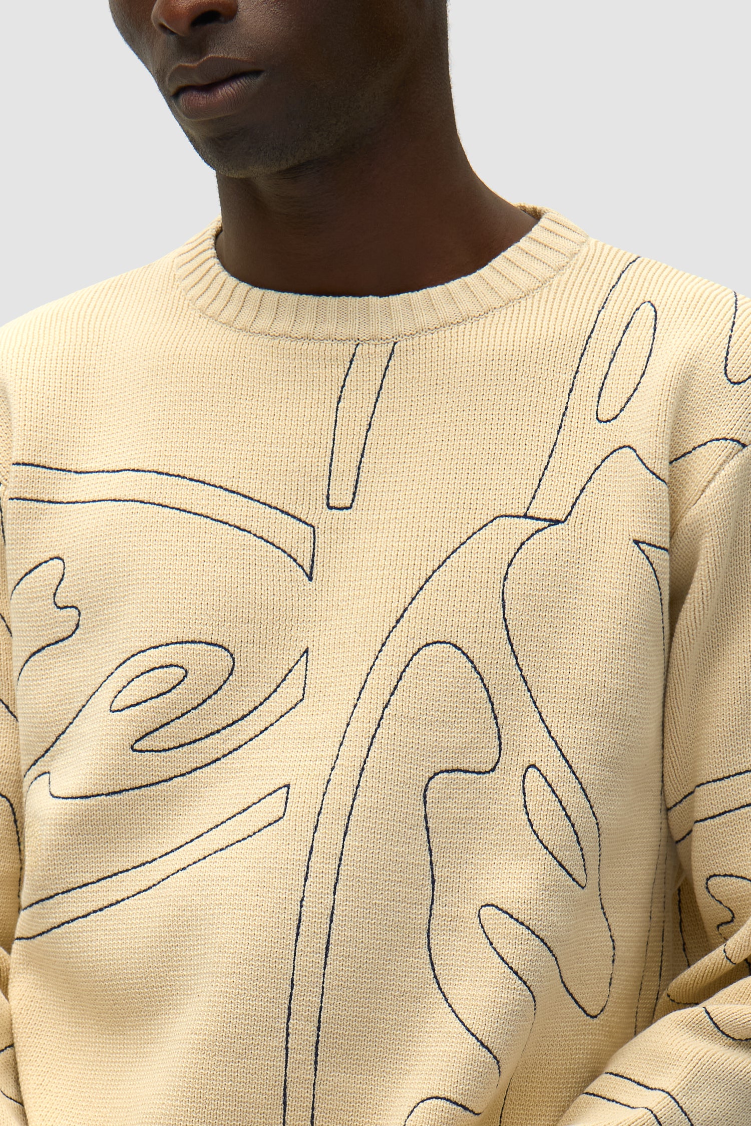 Detail view of Allover Circle Logo Knit in Cream, showing front design