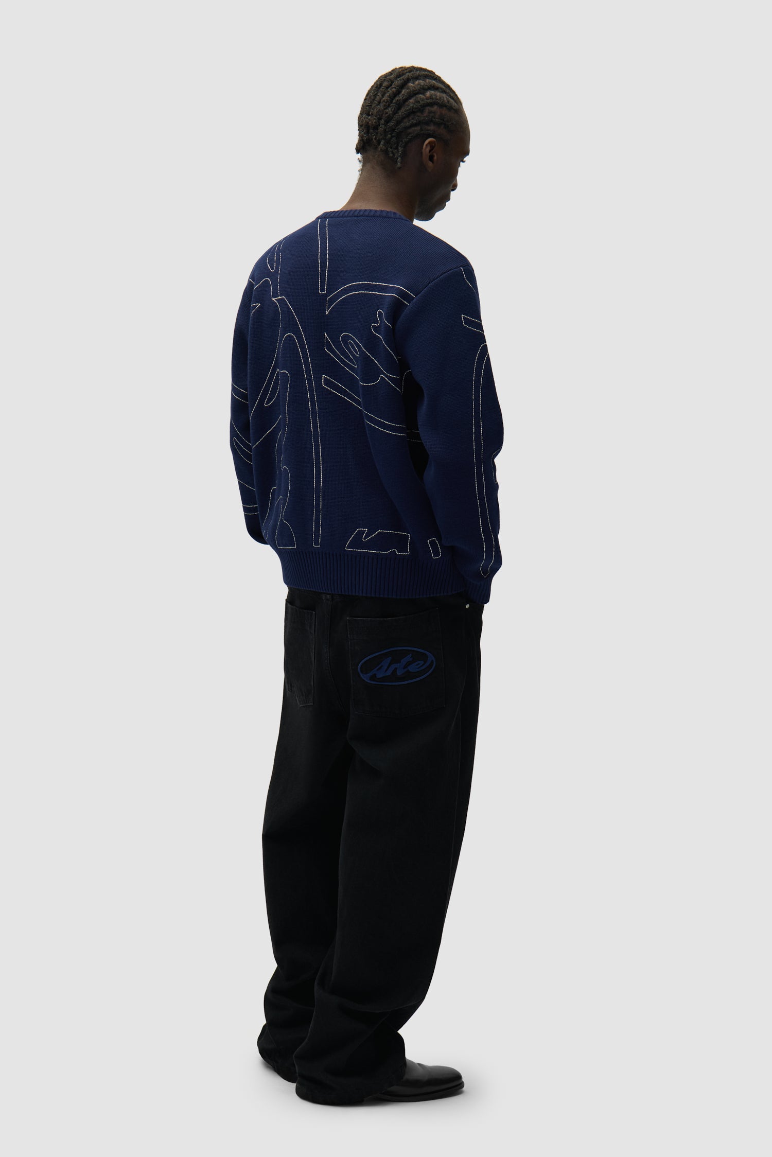 Allover Circle Logo Knit in Navy worn by a model, full-body back view