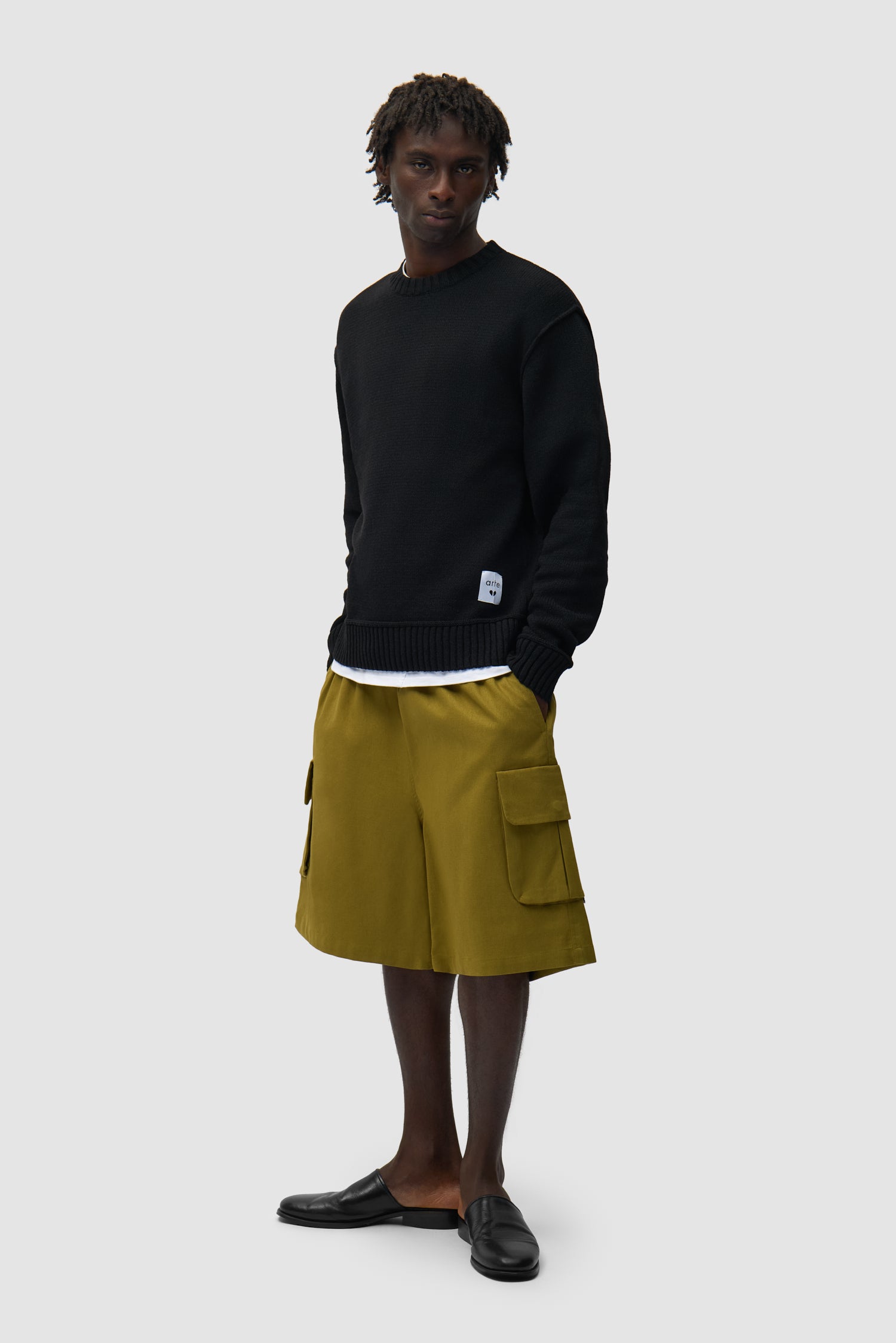 Étiquette réversible en tricot noir portée par un mannequin, vue de profil en pied