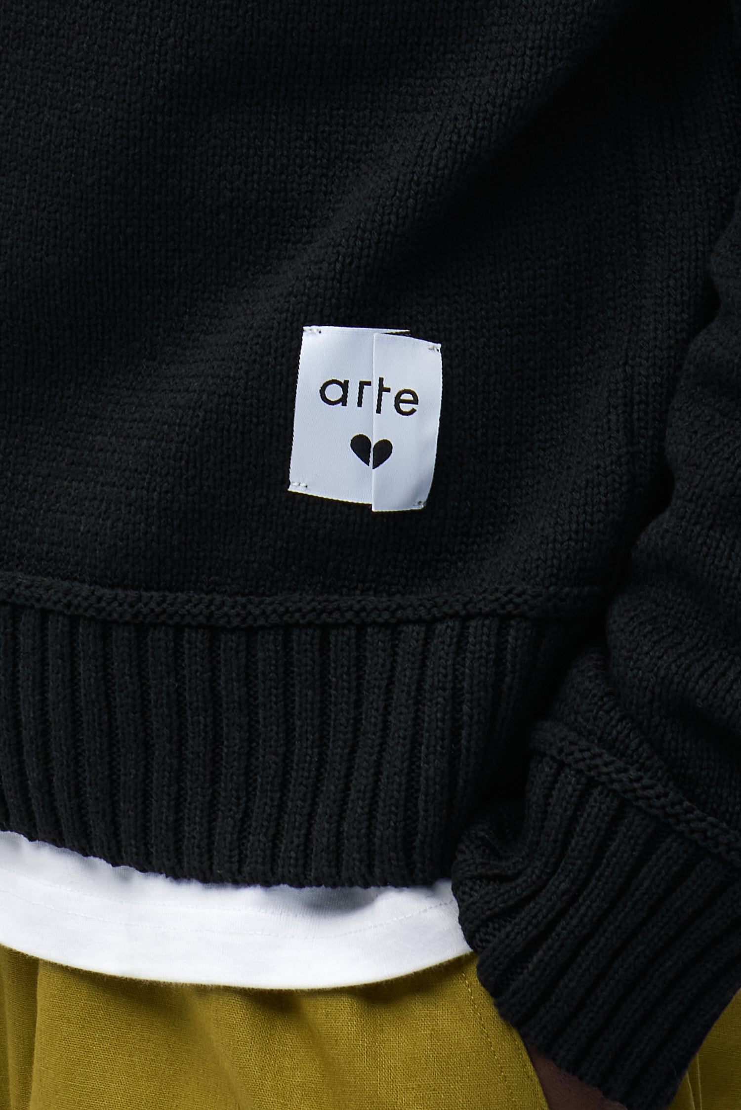 Vue détaillée du pull réversible noir, avec logo sur le devant