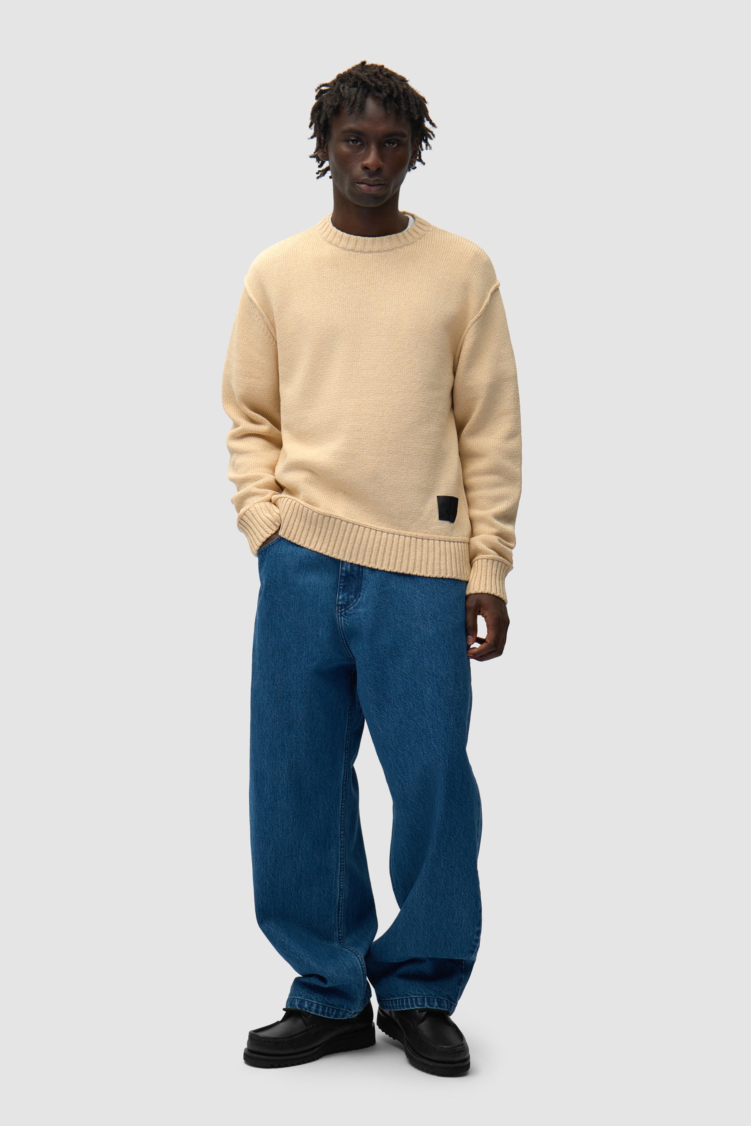 Étiquette réversible en tricot couleur crème portée par un mannequin, vue de face en pied