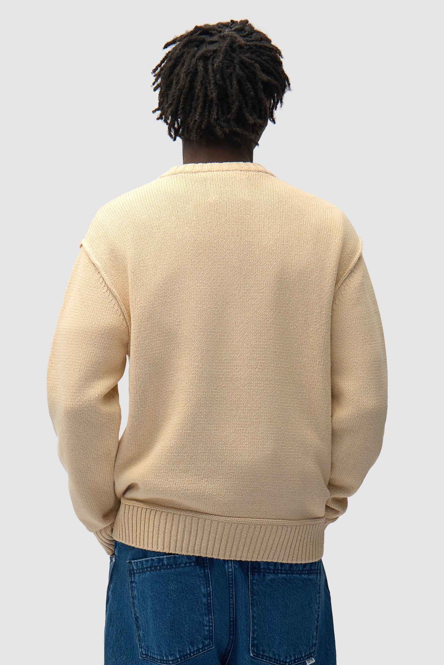 Étiquette réversible en tricot couleur crème portée par un mannequin, vue de dos à mi-corps