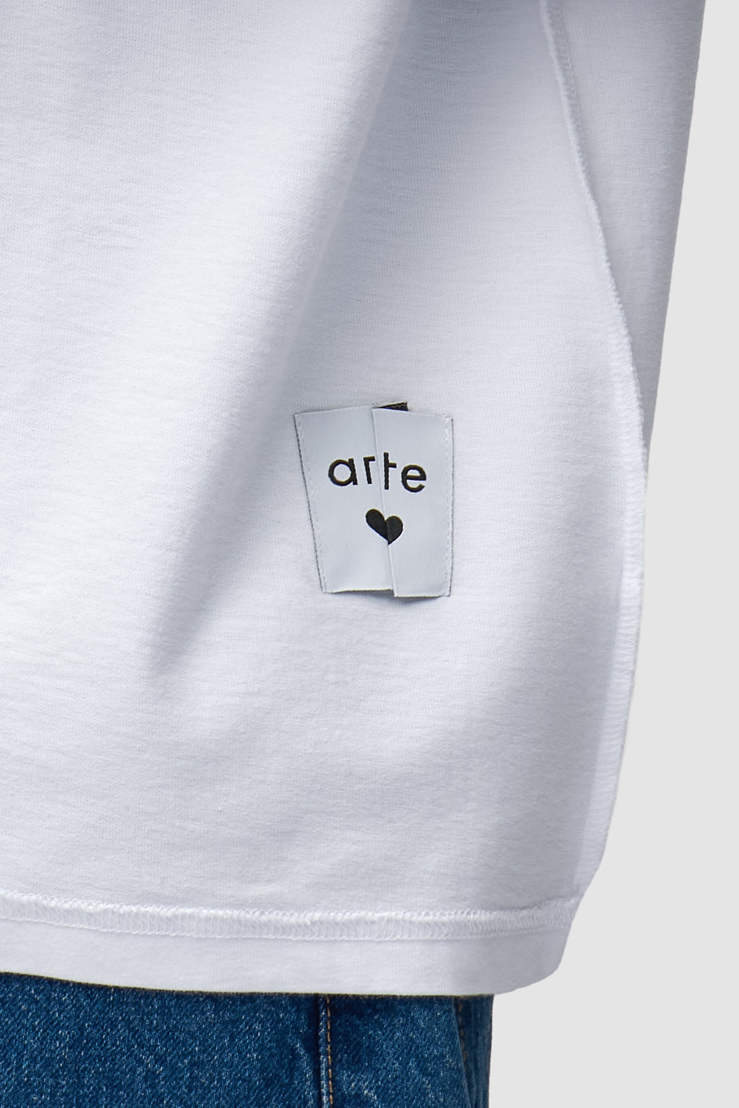Vue détaillée du t-shirt à étiquette réversible en blanc, montrant l'étiquette avant