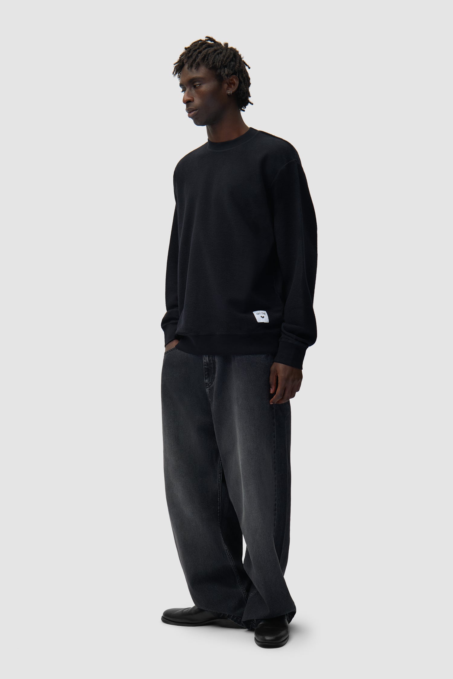 Étiquette réversible Sweat à col rond noir porté par un mannequin, vue de profil en pied