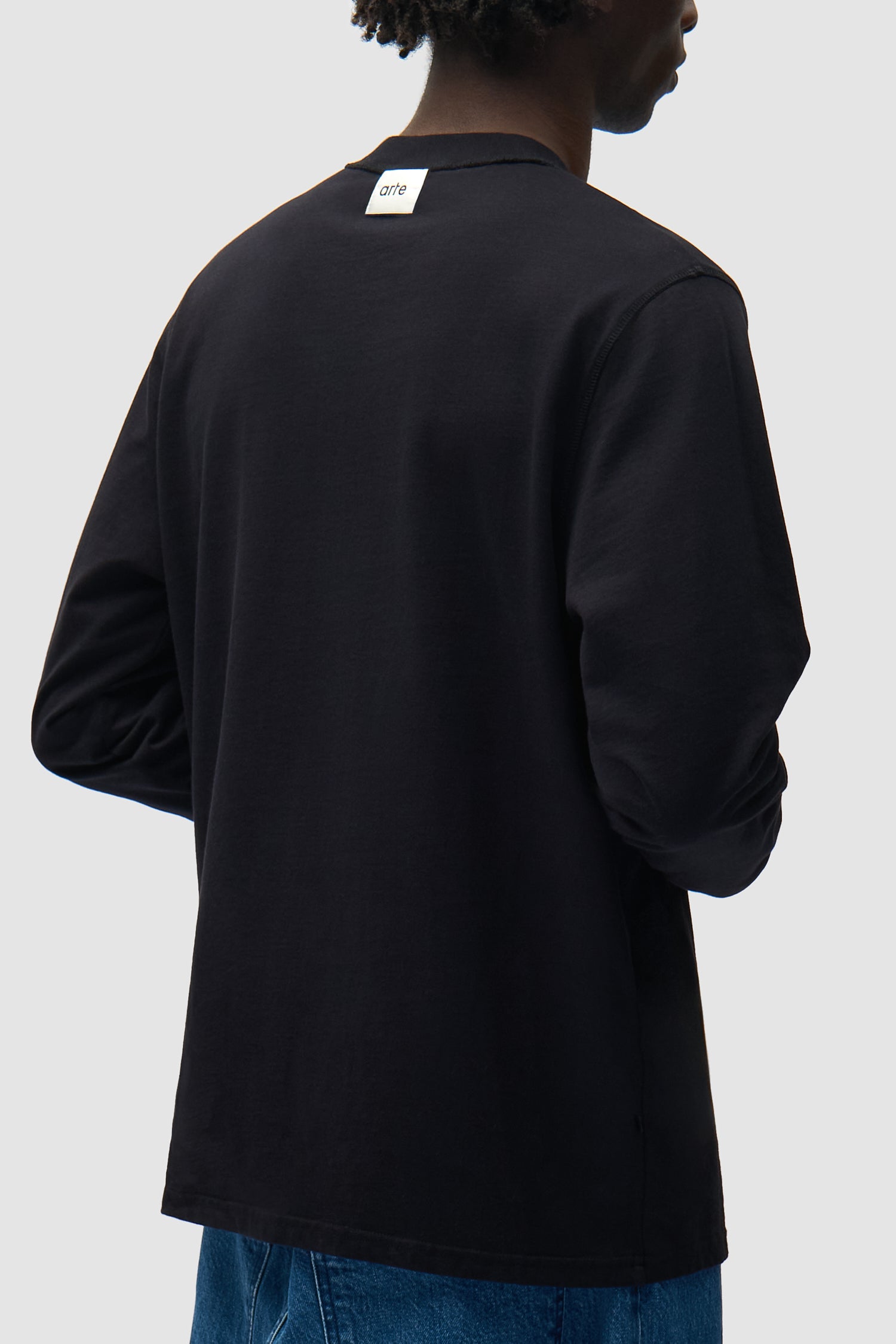 Vue détaillée du t-shirt à manches longues réversible noir, montrant le logo inversé au dos.