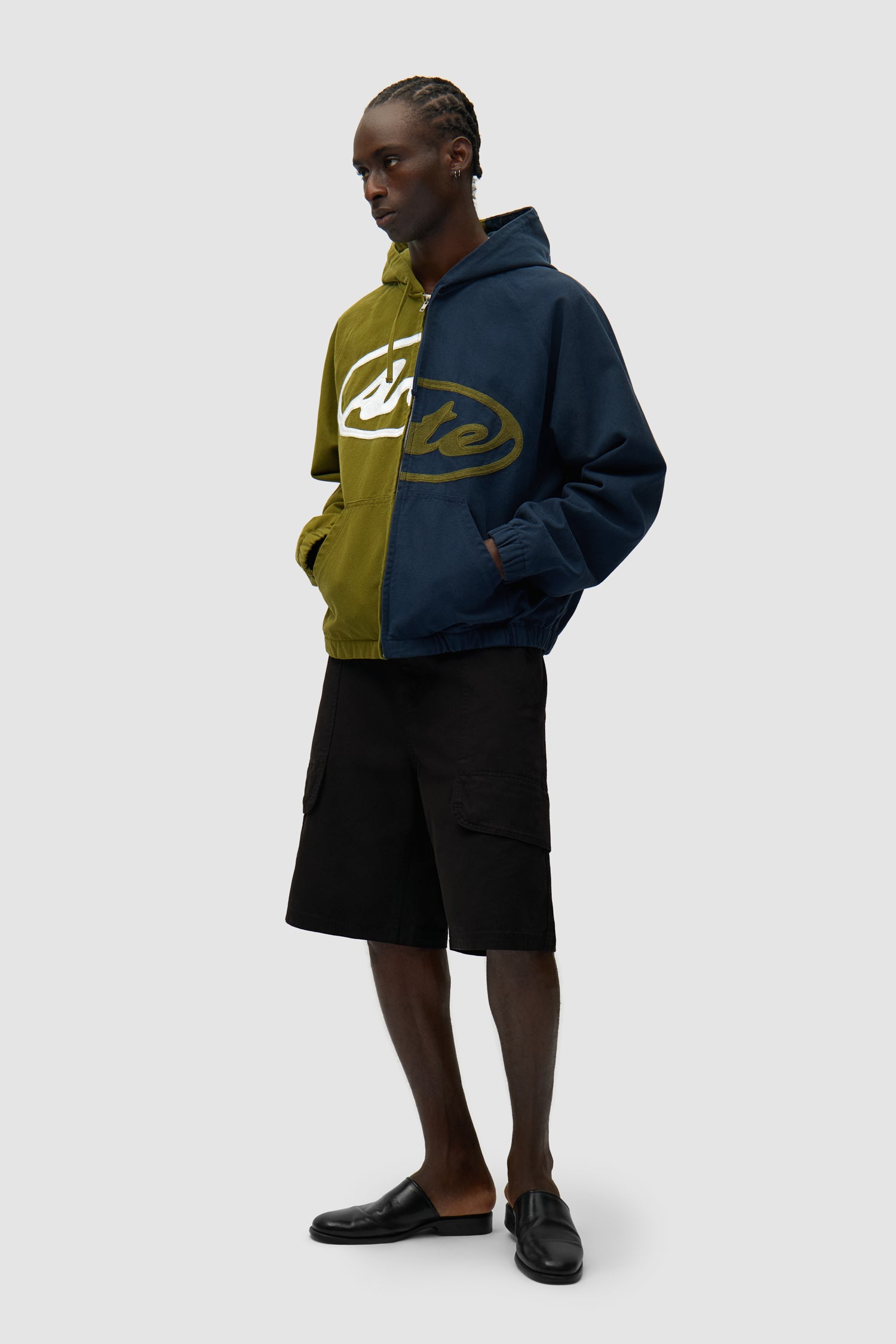 Veste à capuche en toile avec logo divisé, bleu marine/vert, portée par un mannequin, vue de profil en pied
