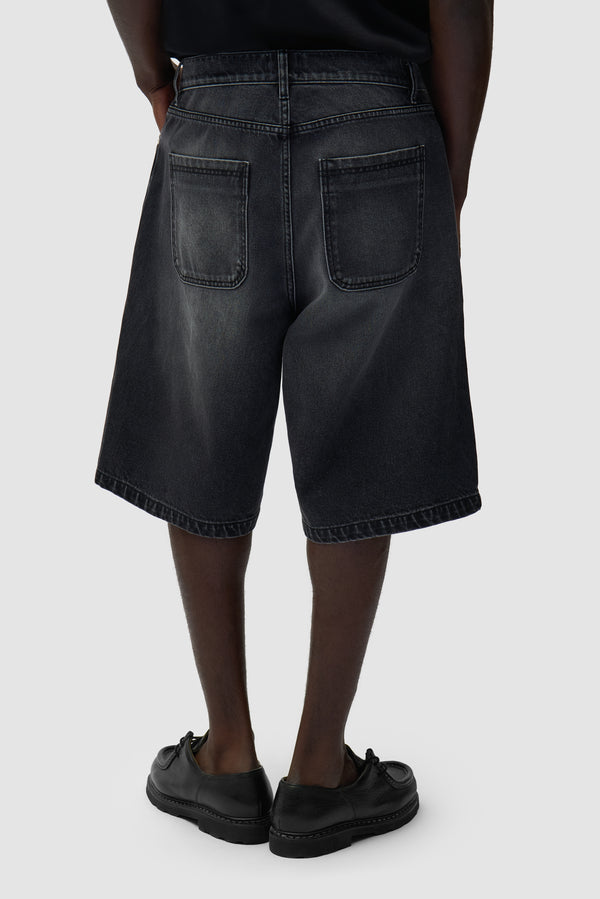 Round pocket Denim Short in Fade Black worn by a model, half-body side view