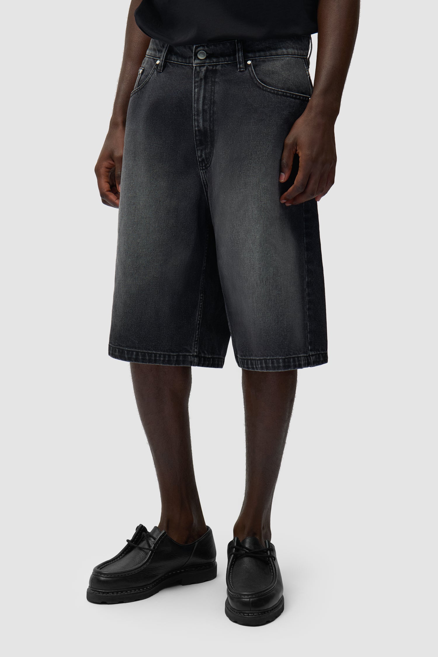 Short en denim à poche ronde, couleur noir délavé, porté par un mannequin, vue de face en pied