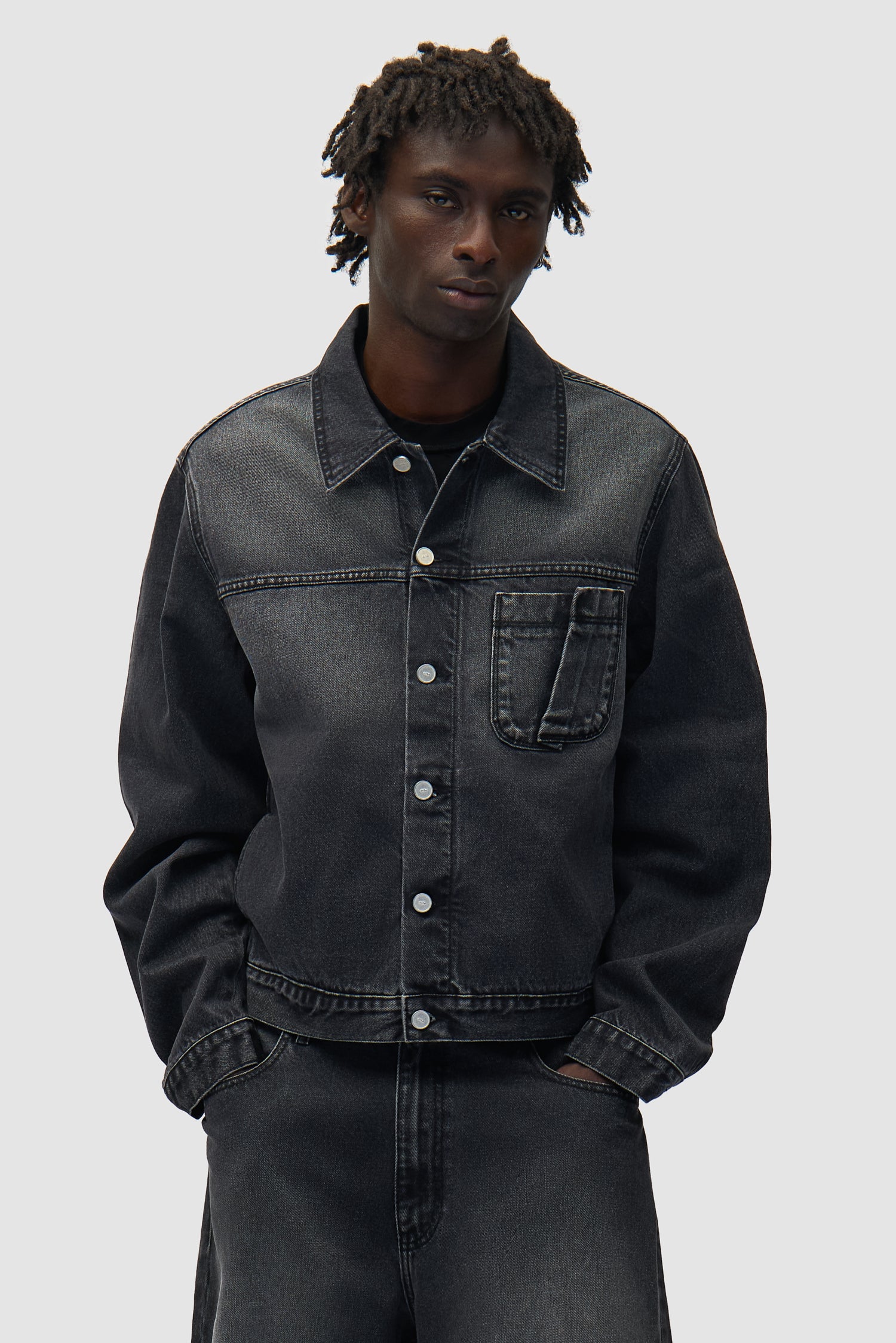 Veste en denim à poches plissées, couleur noir délavé, portée par un mannequin, vue de face, demi-corps