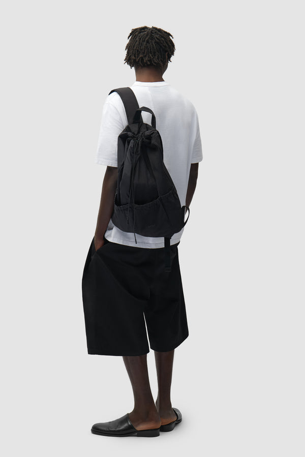 Drawstring Nylon Backpack in Black worn by a model, half-body view