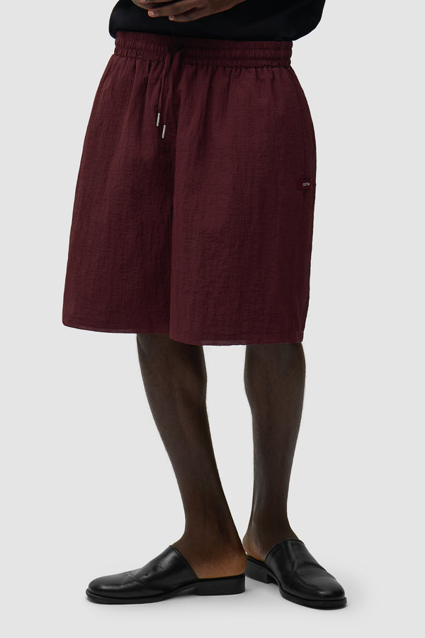 Mesh Shorts in Bordeaux worn by a model, half-body side view