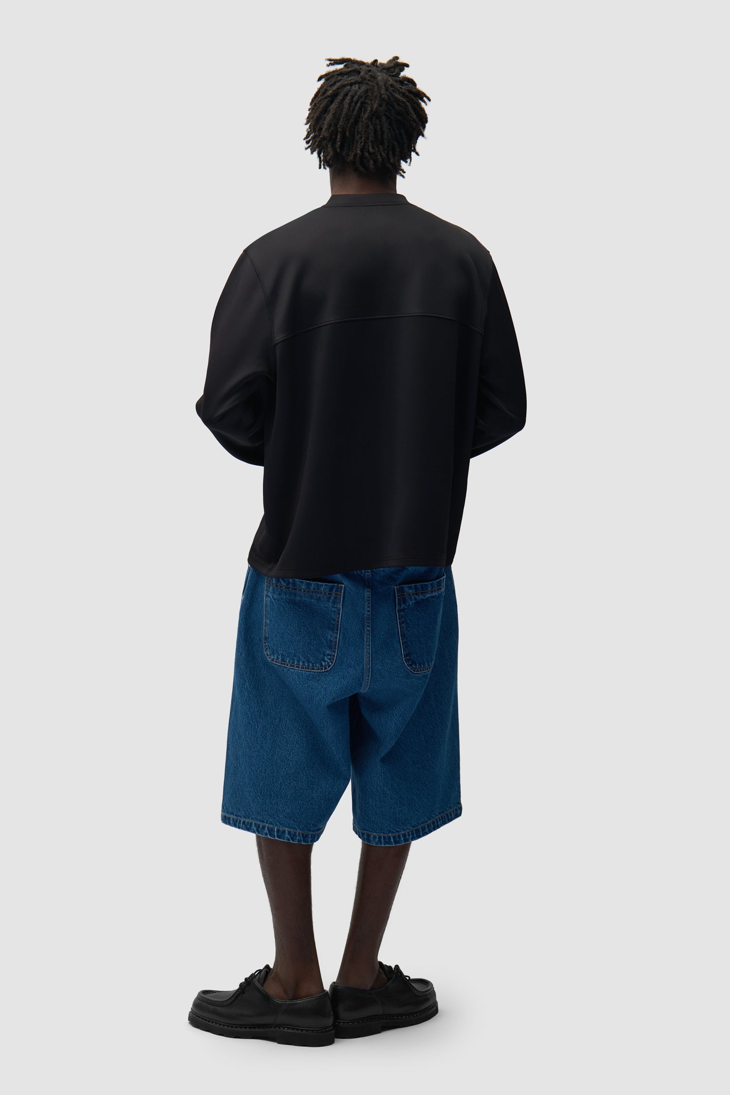 T-shirt à manches longues avec logo circulaire noir porté par un mannequin, vue arrière en pied