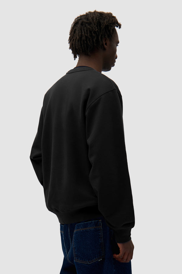 Logo Crewneck in Black worn by a model, half-body back view